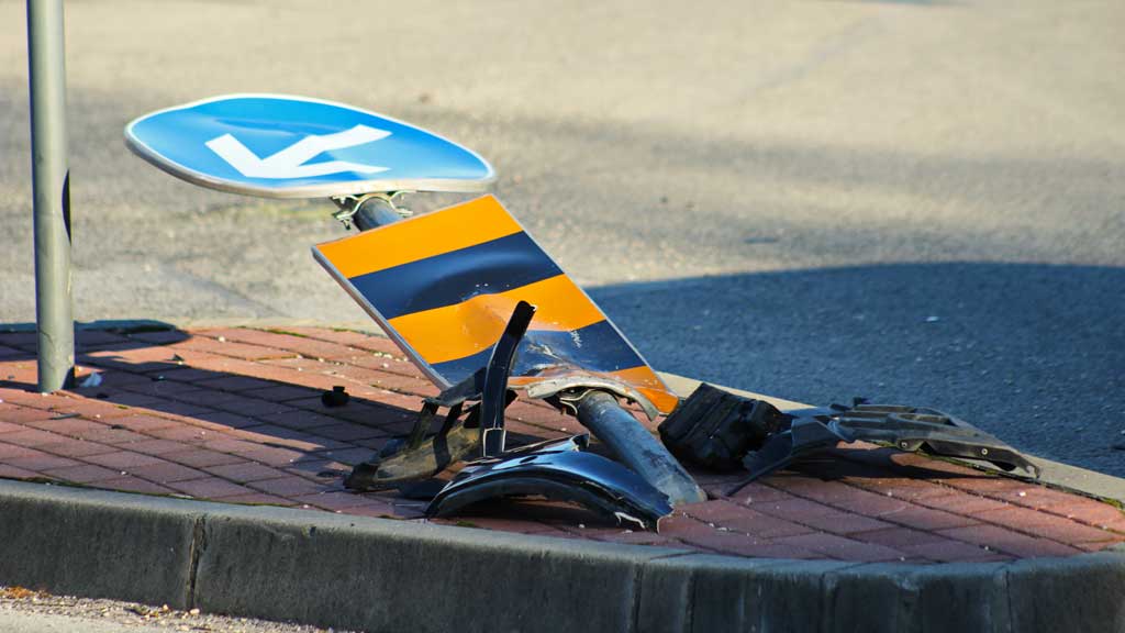 Das Bild zeigt eine Verkehrsinsel mit einem durch einen Unfall zerstörtem Verkehrsschild.