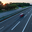 Das Bild zeigt eine Autobahn mit eingigen PKW in Abendsonne